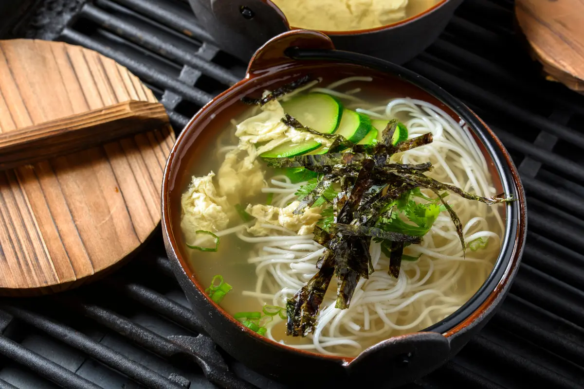 A steaming bowl of golden Chinese egg drop soup garnished with green onions and delicate egg ribbons, showcasing the simplicity and warmth of this traditional dish.